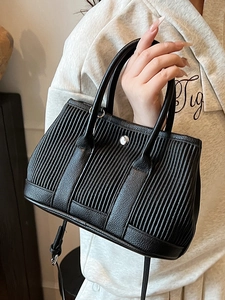 Black pleated bucket bag with silver buckle and adjustable strap shown in hand