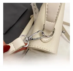Gros plan du crochet pivotant argenté sur un sac à main en cuir beige à grain de litchi