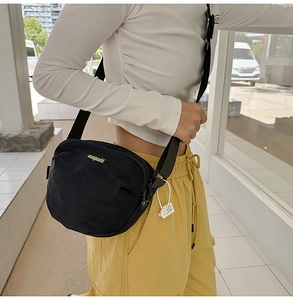 Detail of black nylon crossbody bag with adjustable strap and gold branding for daily commuting