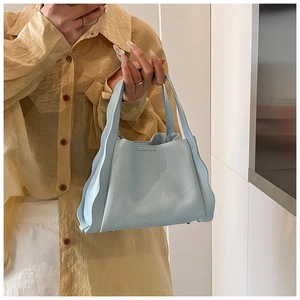 Detail shot of light blue bucket bag with wavy pleated edges and leather texture