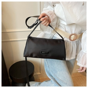 Détail du sac polochon en nylon noir avec écusson logo en cuir et fermeture éclair en métal
