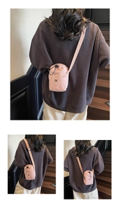 Close-up of light pink drawstring crossbody bag with textured fabric and round black logo