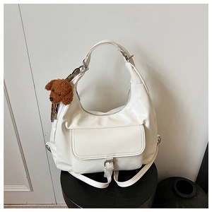 Close-up of a white leather hobo tote bag featuring a front pocket and teddy charm