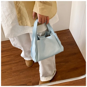 Detail showing wavy edge design and lychee texture on a light blue leather bucket bag