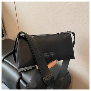 Détail du sac oreiller en nylon noir montrant la bandoulière et l'étiquette de la marque