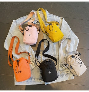 Flat lay of colorful nylon drawstring bucket bags on denim jacket and wooden floor