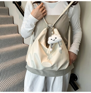 Gros plan d'un sac hobo blanc crème avec pendentif nuage porté par un mannequin