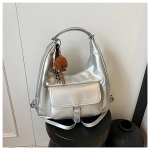 Detail of silver metallic hobo bag featuring buckle pocket and cute plush dog charm