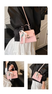 Détails d'un sac rose texture litchi avec fermoir rotatif et charm en dentelle