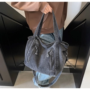Détail du sac cabas en denim délavé avec texture vintage et poches zippées pratiques