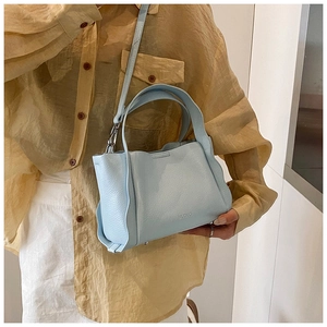 Lifestyle shot of a light blue leather bucket bag with top handle and shoulder strap