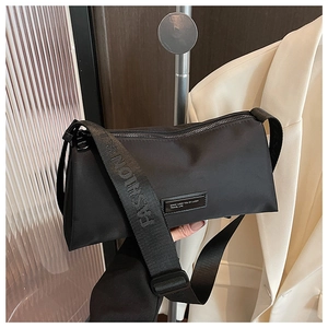 Détail du sac bandoulière en nylon noir avec sangle mode et écusson logo décoratif