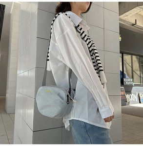 Close-up of light blue nylon crossbody bag with yellow top-design embroidery detail