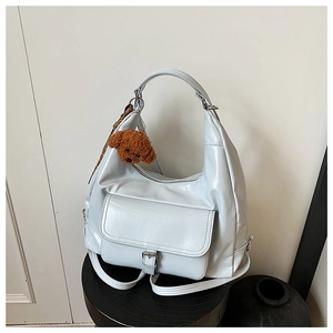 Detail of light blue glossy hobo bag with buckled pocket and brown teddy bear charm