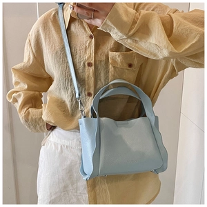 Close-up of light blue bucket bag showing wavy pleated edges and silver protective feet