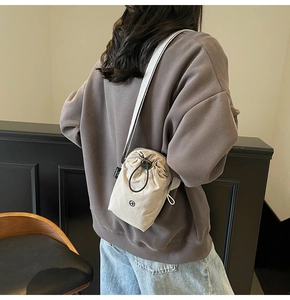 Detail of beige drawstring crossbody bag in lightweight waterproof nylon fabric
