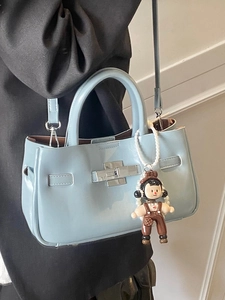 Minimalistische lichtblauwe emmertas van olie-was leer met een schattige pop-hanger
