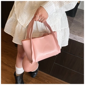 Close-up of pink lychee leather bucket bag showing soft texture and metal handle details