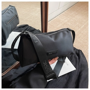 Détail du sac bandoulière en nylon noir avec bandoulière large texturée et fermeture éclair