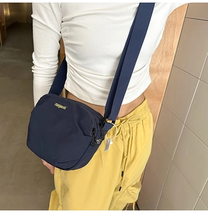 Detail of the dark blue nylon crossbody bag with wide shoulder strap and yellow lettering