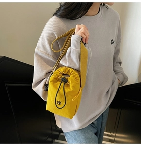 Yellow nylon drawstring crossbody bag shown on model with adjustable strap and N logo