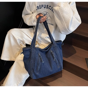 Gros plan détaillé d'un sac fourre-tout en denim bleu foncé avec poches zippées et pompons