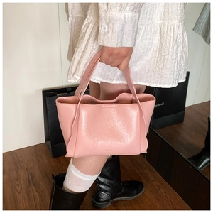 Detail of pink lychee leather bucket bag with wavy folds and delicate embossed lettering