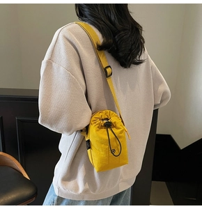 Detail of yellow nylon drawstring bucket bag on model with adjustable strap