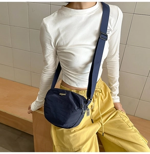 Detail view of the waterproof dark blue nylon crossbody bag with golden logo and zipper