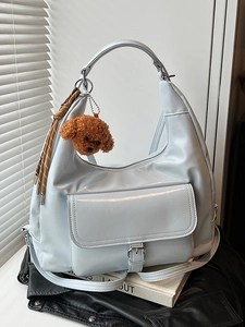 Minimalist light blue hobo tote bag with plush teddy charm and woven tassel detail