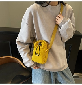 Detailed view of yellow nylon crossbody bag with drawstring closure and logo on model