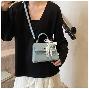 Détail du sac bleu clair en cuir grainé avec nœud en dentelle et chaîne de perles fines