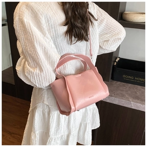 Pink lychee grain leather bucket bag shown from a back view on a female model