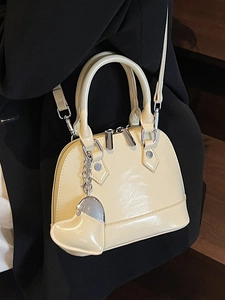 Beige shell-shaped handbag with glossy finish, silver hardware and heart charm