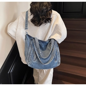 Détail du sac cabas en denim bleu montrant plusieurs sangles et texture délavée