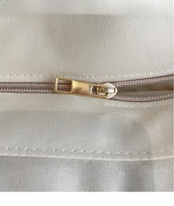 Gros plan sur la fermeture éclair dorée et la texture tissée du sac de plage crème