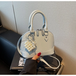Dettaglio mini borsa a conchiglia blu con ciondolo a cuore di perle e fiocco argento