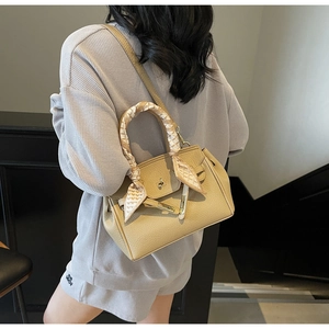 Detail of light brown lychee leather handbag with decorative silk scarf and bee buckle