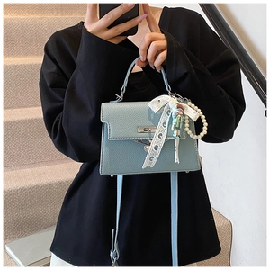 Détail du sac bleu clair à motif litchi avec nœud en dentelle et breloque perle