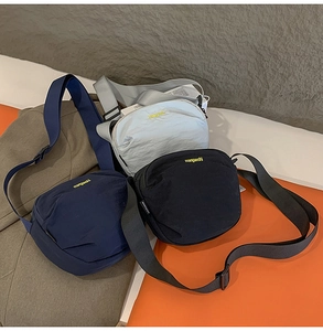 Detailed view of three nylon crossbody bags in grey, dark blue, and black with logo