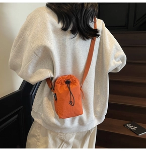 Detailed view of the bright orange drawstring crossbody bag with waterproof nylon texture