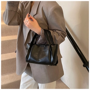 Close-up of black bucket bag with lychee grain leather texture and wide top handle