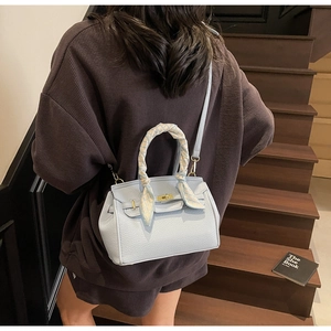 Back view of a light blue leather handbag with silk scarf handle and metal clasp