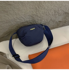 Detailed close-up of navy canvas crossbody bag with brand logo and durable shoulder strap