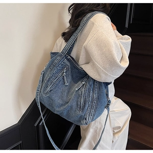 Détail d'un sac fourre-tout en denim bleu délavé avec poches zippées et texture vintage