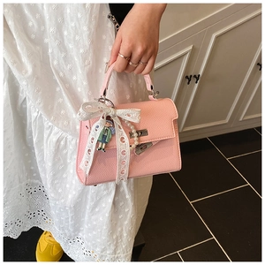 Gros plan détaillé du sac rose en cuir avec nœud en dentelle et breloque perle
