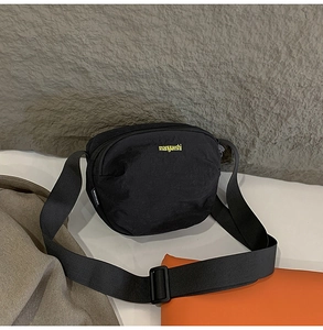Close-up of black casual crossbody bag with yellow embroidered logo and adjustable strap