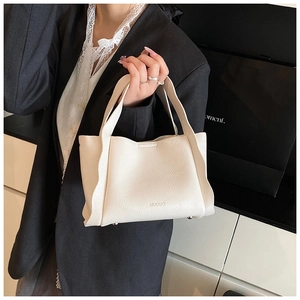 Detail of white bucket bag featuring wave pleated edges and premium lychee pattern leather