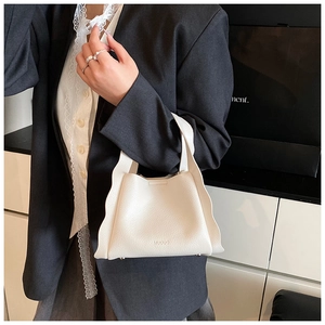 Close-up of white bucket bag featuring lychee texture leather and wavy ruffle edge detail