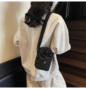 Detail of minimalist black drawstring crossbody bag with adjustable wide fabric strap